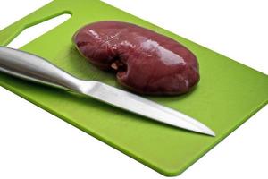 Fresh pork kidney on a cutting board. Fresh raw kidney for dog. photo