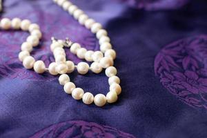 Luxury pearl necklace and bracelet on a purple background. photo