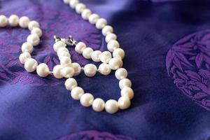 Luxury pearl necklace and bracelet on a purple background. photo