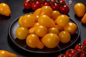 pequeños tomates amarillos en forma de pera en un plato de cerámica sobre una mesa de hormigón oscuro foto