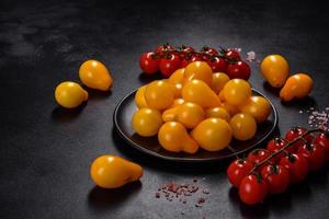 pequeños tomates amarillos en forma de pera en un plato de cerámica sobre una mesa de hormigón oscuro foto