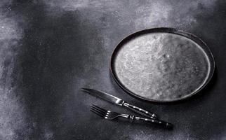 Black plate on a black background. Flat lay, top view, copy space photo