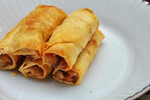 los rollitos de primavera fritos colocados en un plato blanco, los rollitos de primavera fritos son un plato asiático popular. foto