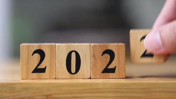 Wooden cube blocks with number 2022 changing to 2023 by hand for New year concept video
