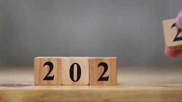 Wooden cube blocks with number 2022 changing to 2023 by hand for New Year concept video