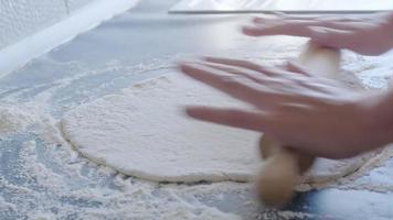 Cook rolt het deeg voor pizza uit met een deegroller. de kok rolt het deeg uit, chef is aan het bakken, bakkerijproducten, deeg maken video