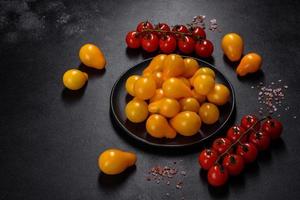 pequeños tomates amarillos en forma de pera en un plato de cerámica sobre una mesa de hormigón oscuro foto