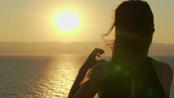 frau, die herz mit ihren händen macht. Silhouette weiblicher Arme, die ein Symbol der Liebe mit Sonnenuntergang im Inneren zeigen. video