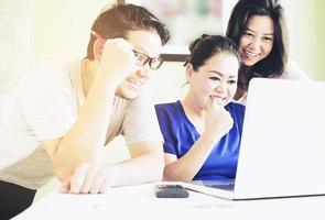 Two women and one man are happily looking at computer in modern office photo