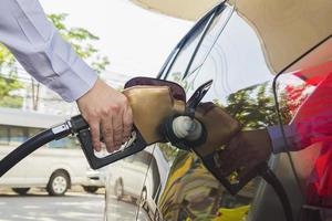 hombre poniendo gasolina en su coche en una gasolinera de bomba foto