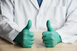 Middle part of doctor sitting and put green glove showing thumb up cheer sign photo