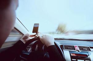 primer plano de un hombre conduciendo un coche peligrosamente mientras usa el teléfono móvil foto