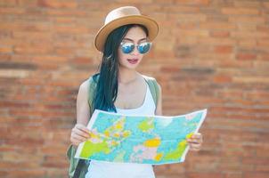 mujer viajera turística mirando el mapa mientras camina por una calle - concepto de viaje de mochila callejera foto