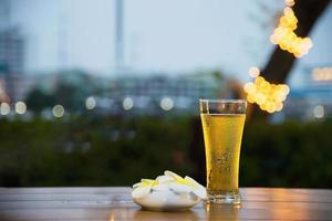 vaso de cerveza fresco en el crepúsculo - relájese con cerveza en el concepto de jardín foto