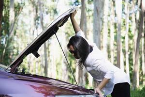 Asian woman calling repairman or insurance staff to fix a car engine problem on a local road - people with car problem transportation concept photo