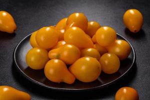 pequeños tomates amarillos en forma de pera en un plato de cerámica sobre una mesa de hormigón oscuro foto