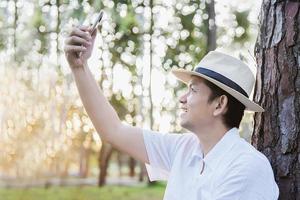 Asian man with mobile phone in forest tree nature - people in spring nature and technology concept photo
