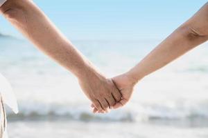 Asian couple is holding hand near to the sea photo