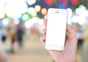 Hand showing smart phone with isolated screens display with defocused night street festival photo