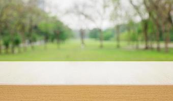 Empty wooden deck table over blurred tree with bokeh background photo