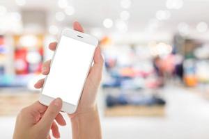 mano de mujer que muestra un teléfono inteligente con pantallas aisladas en un mercado o tienda por departamentos foto
