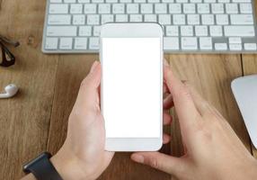 woman hand holding empty screen of smart-phone on wood desk work. photo