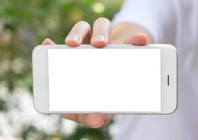 mujer sosteniendo un teléfono inteligente en la mano con un fondo verde de primavera foto