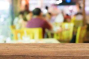 mesa de madera con gente borrosa en el café como fondo para exhibir productos foto