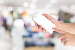 mano de mujer que muestra un teléfono inteligente con pantallas aisladas en un mercado o tienda por departamentos foto