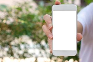 mujer sosteniendo un teléfono inteligente en la mano con un fondo verde de primavera foto