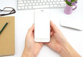 woman hands holding empty screen of smartphone on white desk work. photo