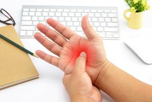 Young man with hand pain with red alert accent photo