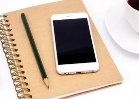 Smart phone and notebook with empty screen on white table photo