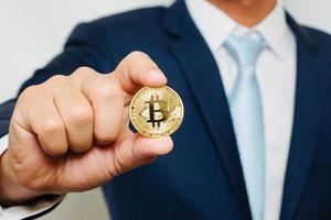 businessman in suit holding a golden bitcoin photo