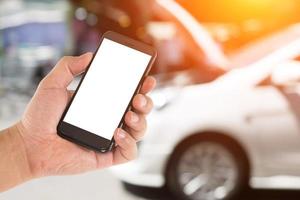 Mobile phone in hand on car repair service center blurred background photo