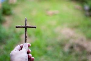 His left-hand holding a cross. right copyspace for entering text. Closeup photographing with background green and blurred. photo