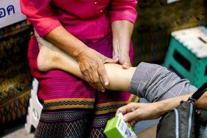 las manos de primer plano de la dama masajeadora son toque de demostración y masajean la pierna de un turista en la feria cultural de tailandia, tokio, japón. foto