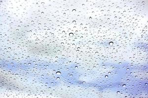 Raindrops on glass under the blue sky background. photo