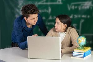 el chico y la chica se están preparando juntos para el examen de matemáticas. estudiantes juntos usando una computadora portátil. educación en línea durante la pandemia de coronavirus foto