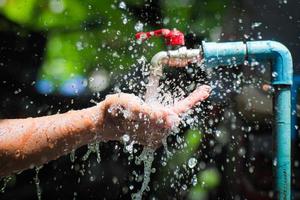 concepto de agua en la vida cotidiana. manos sosteniendo el agua que fluye del grifo. agua salpicando del grifo foto