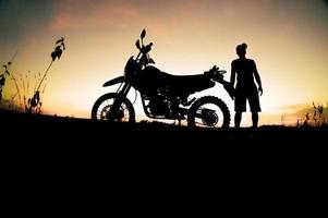 siluetas masculinas y motos de motocross. parque para relajarse en las montañas por la noche. concepto de ocio y viajes de aventura foto