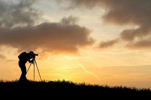 la silueta de un fotógrafo profesional se centra en disparar en un hermoso prado. foto