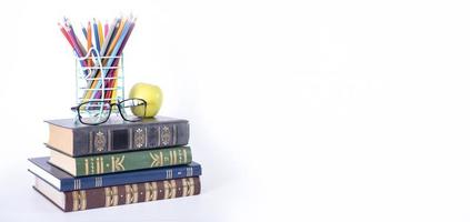 A stack of books, study guides, textbooks, glasses, and pencils in a text copy holder. photo