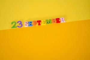 September 23 on a yellow and paper background with wooden letters and numbers in different colors. photo