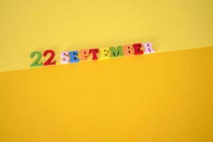 September 22 on a yellow and paper background with wooden letters and numbers in different colors. photo