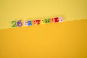 23 de septiembre sobre un fondo amarillo y de papel con letras y números de madera en diferentes colores. foto