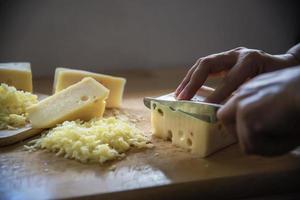 Woman preparing cheese for cook using cheese grater in the kitchen - people making food with cheese concept photo