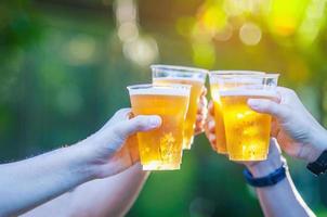 Celebration beer cheers concept - close up hands holding up glasses of beer of people group in outdoor party during their victory competition or successful task meeting photo