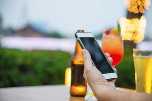 Man using mobile during happy time relax in restaurant with softdrink and green garden background - people relax with technology lifestyle concept photo