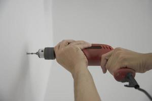 Man using hand drill device for installing home furniture at new white wall - people DIY home furniture installation concept photo